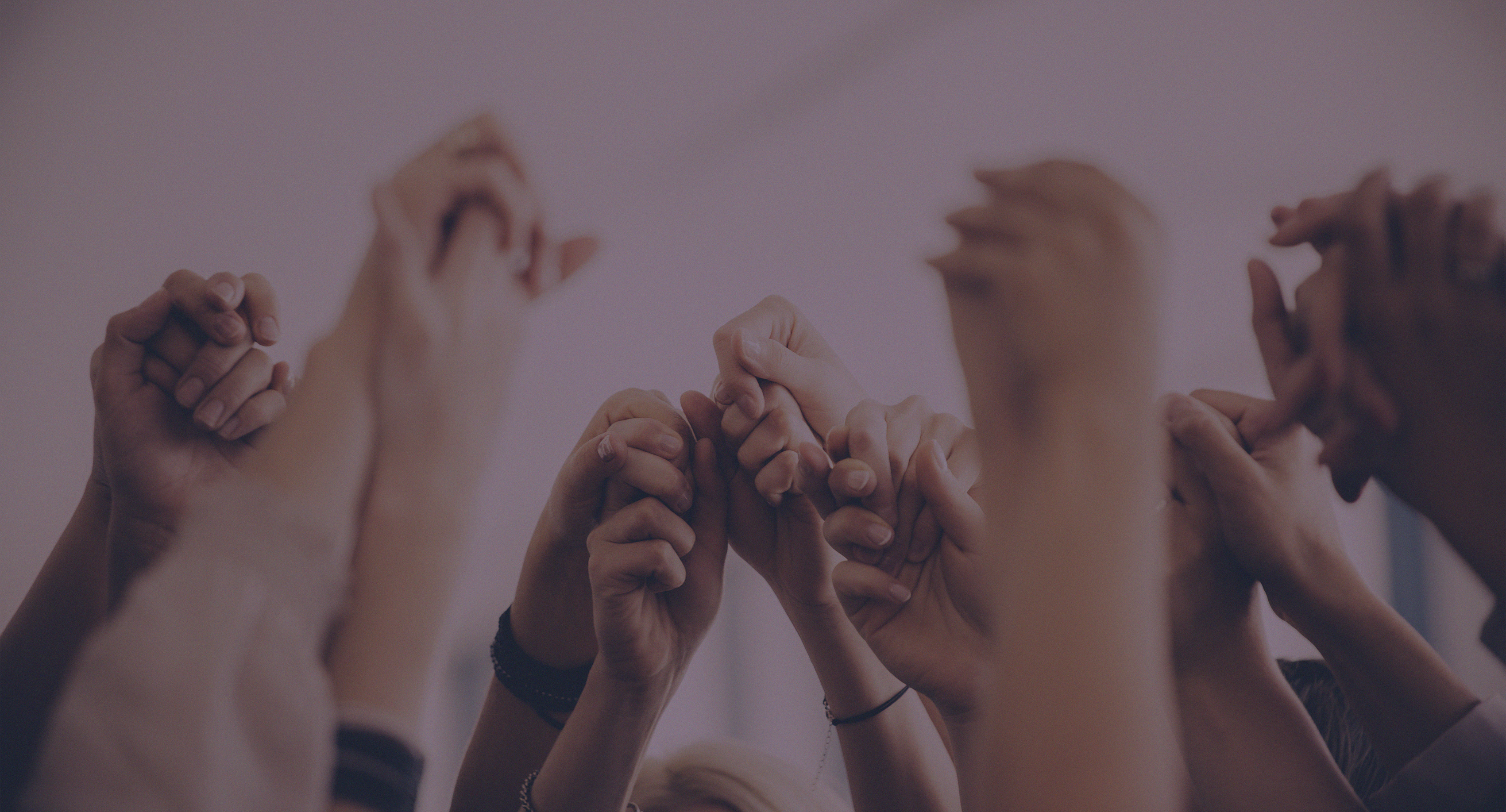 people holding hands above heads in a circle